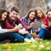 Group of young people using digital tablet and smart phone outdoors.